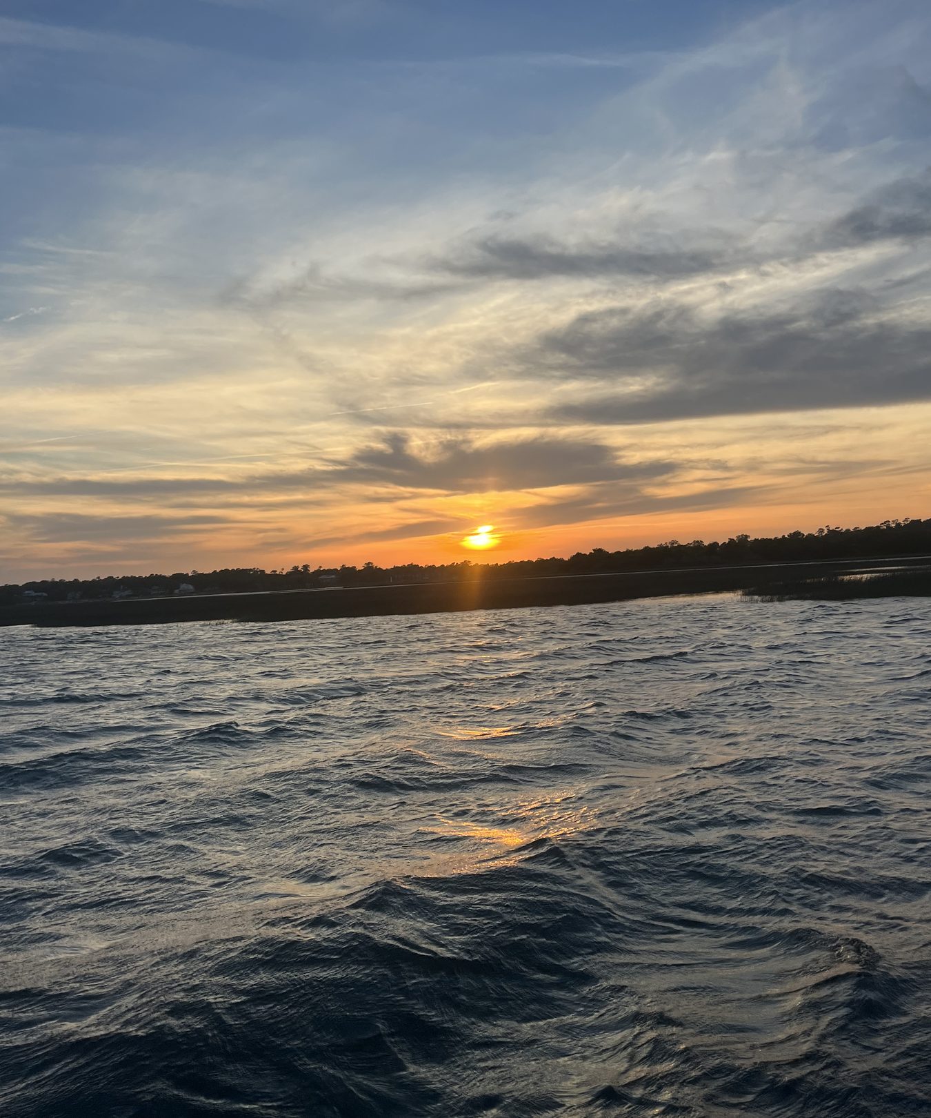 Sun setting over the shoreline across Gulf waters